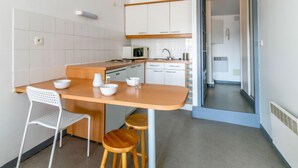 A modern kitchen with white cabinets, a wooden countertop, and a dining area with stools. - Casa Itzuli by Interhome (Bayonne)