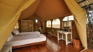 A tented accommodation with a bed, a desk, and a chair. - Wild Glamping (Rangala)