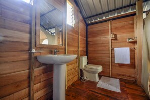 A wooden cabin bathroom with a sink, toilet, and mirror. - Wild Glamping (Rangala)