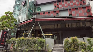 Un hôtel moderne avec une façade en verre, des touches de rouge et une enseigne bien visible.