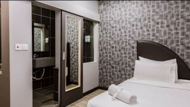 Une chambre d’hôtel comprenant un lit, un dressing et un espace douche.