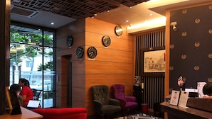 Un espace d’accueil moderne, doté de panneaux en bois, de plusieurs horloges et d’un comptoir de réception.