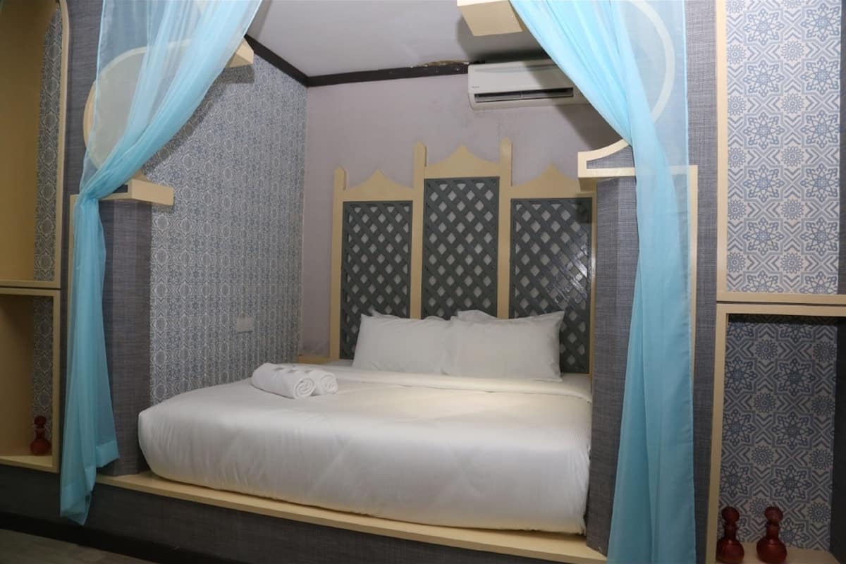 Ein Bett mit Baldachin, Wänden mit Muster und einem Kopfteil mit Rautenmuster.