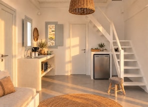 A modern kitchen with a built-in dishwasher, a wooden stool, and a staircase leading to an upper level.