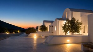 A modern building with a flat roof, white walls, and a few trees.