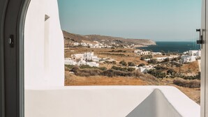 A view from a room with a large window, overlooking a coastal landscape with white buildings and a clear sky. - Bianco Diverso Suites (Santorini)