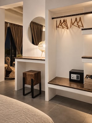 Une chambre à coucher moderne comprenant un lit, une table de chevet, un petit tabouret en bois, un miroir rond, une lampe fixée au mur et un porte-manteau.