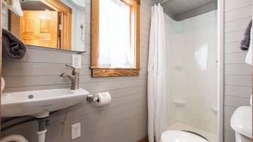A bathroom with a wooden vanity, a sink, a toilet, and a shower area.
