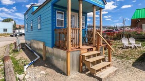 A two-story blue house with a porch, wooden steps, and a small deck.
