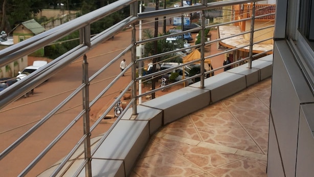 A balcony with a view of a street and buildings. - Hotel Com Apartment (Entebbe)