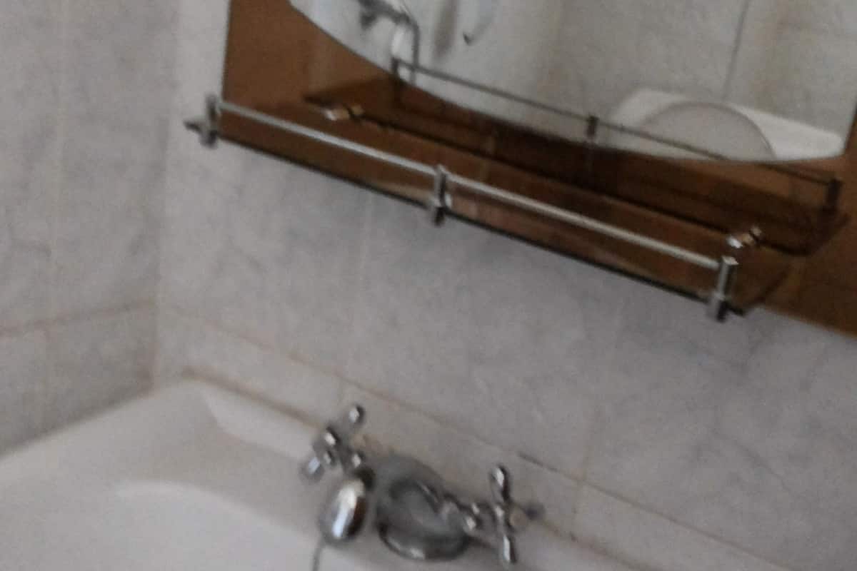 A bathroom with a sink, mirror, and towel rack.