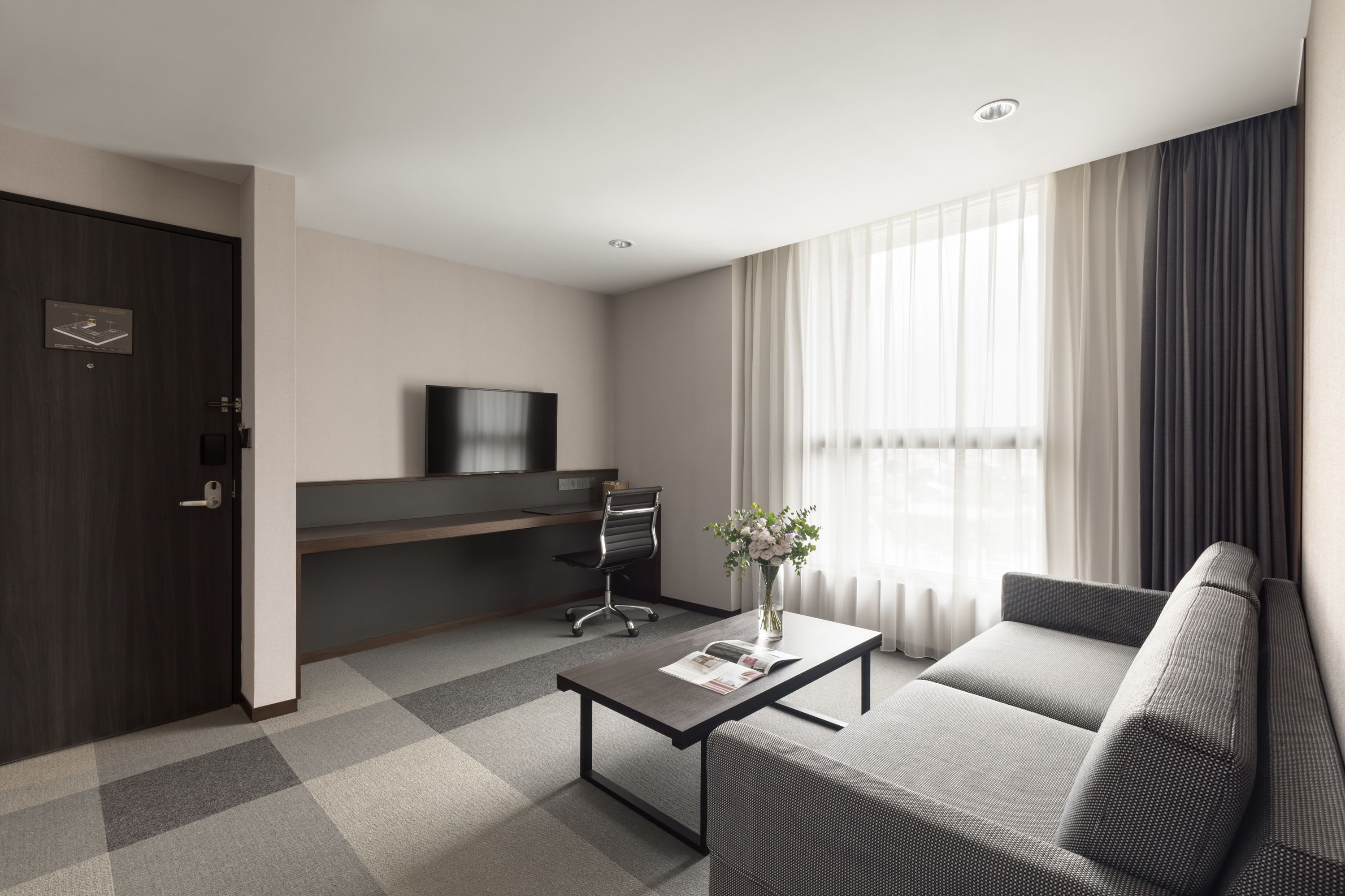 Habitación de hotel moderna con sofá, una mesa de centro, televisor y escritorio.