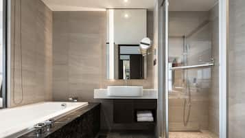 A modern bathroom with a large bathtub, a glass-enclosed shower, and a vanity with a mirror.