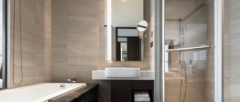 A modern bathroom with a large bathtub, a glass-enclosed shower, and a vanity with a mirror.