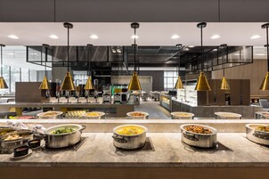 A modern buffet setup with multiple food stations and overhead lighting.
