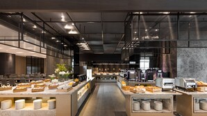 A modern hotel lobby with a central reception desk, seating area, and a buffet with various food items. - Lakeshore Hotel Tainan (Tainan)