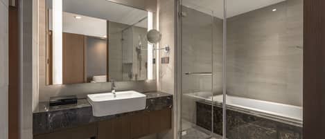 A modern bathroom with a glass-enclosed shower, a large mirror, a white sink, and a wooden vanity.