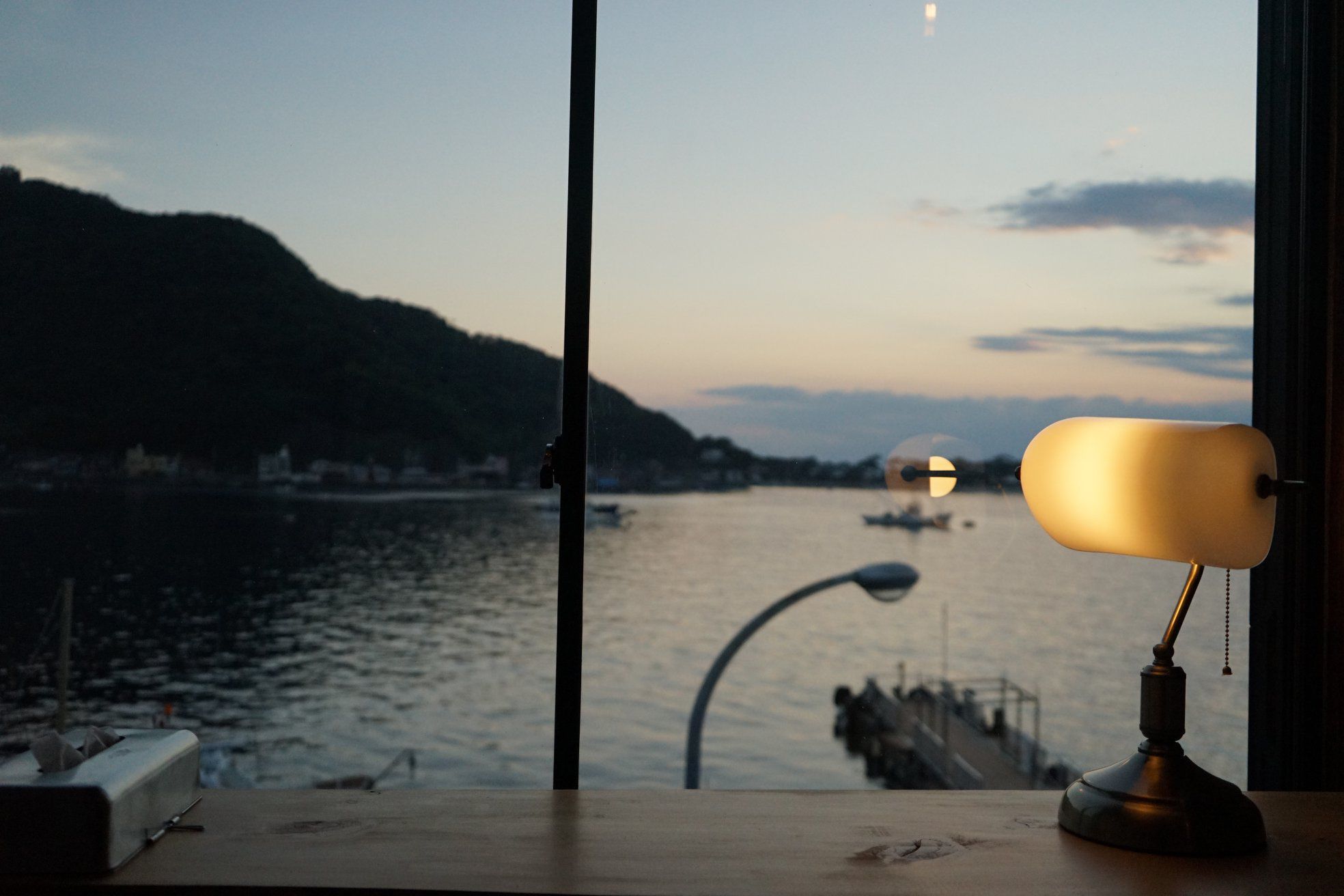 Ein Schreibtisch mit einer Lampe und Blick auf einen Fluss im Abenddämmerung.