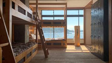 A bunk bed room with a view of the water, wooden floors, and a set of lockers.