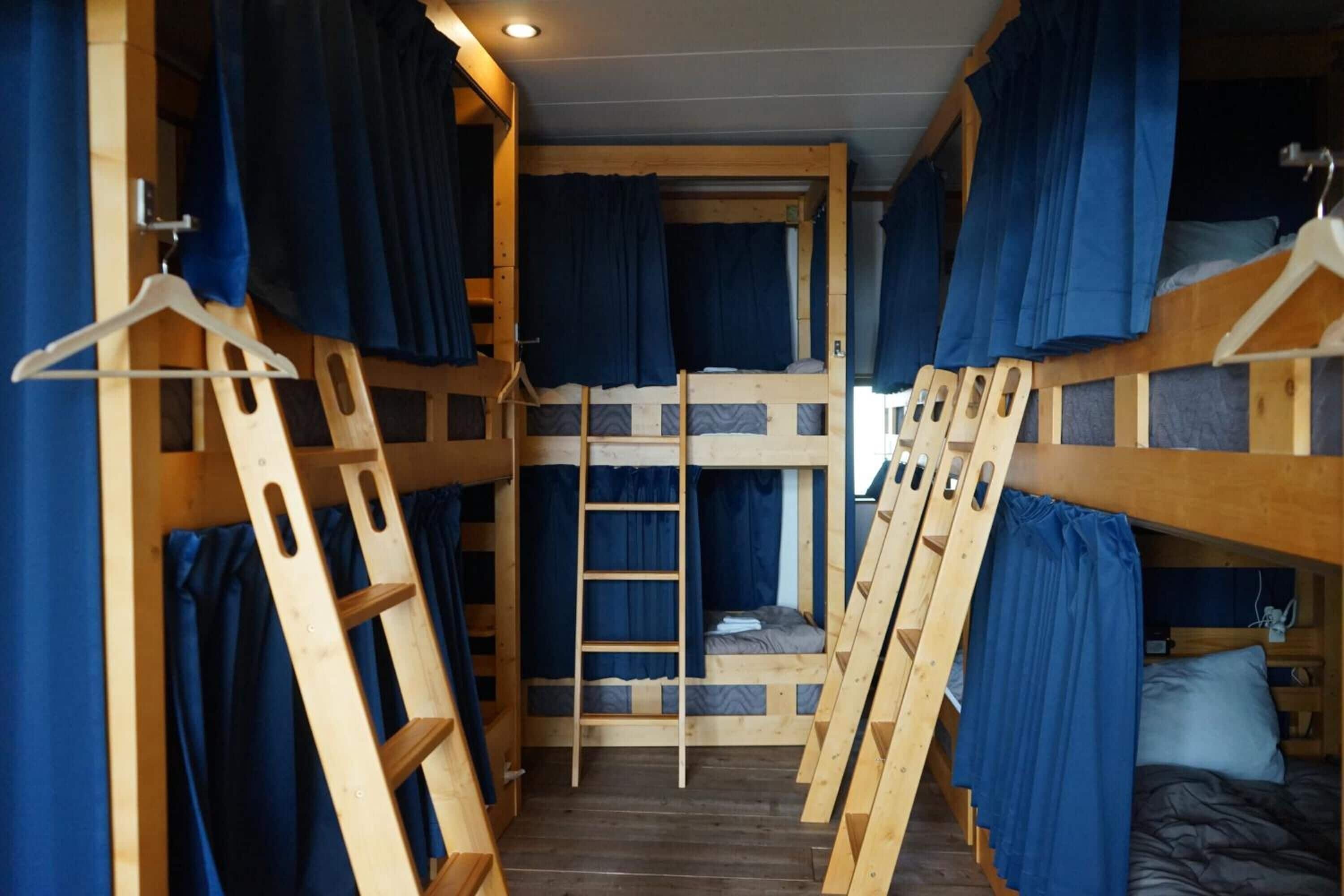 Habitación con literas de madera y cortinas azules.