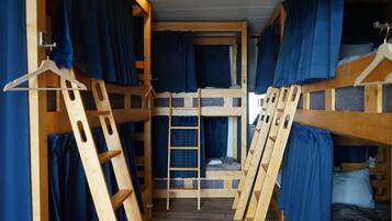 Habitación con literas de madera y cortinas azules.