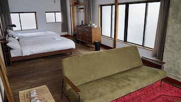 A hotel room with a bed, a sofa, a dresser, and a window.