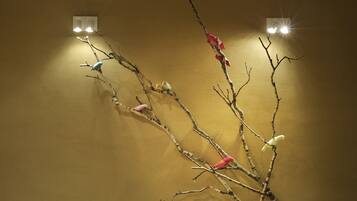 Un mur orné de branches et de petits oiseaux, deux appliques murales et une surface murale texturée.