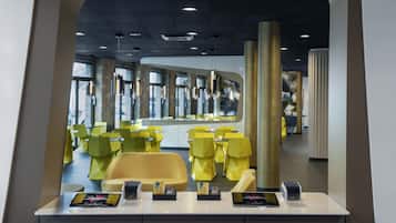 Un intérieur moderne avec des chaises et des tables jaunes, un comptoir d’accueil et une grande fenêtre en arrière-plan.