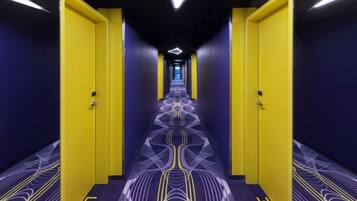 Un pasillo con puertas amarillas, alfombra estampada y lámpara moderna.