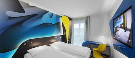 A modern hotel room with a large bed, a desk, and a TV on the wall.