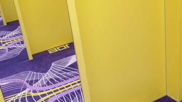 A hallway with yellow walls and purple carpet featuring a white abstract design.
