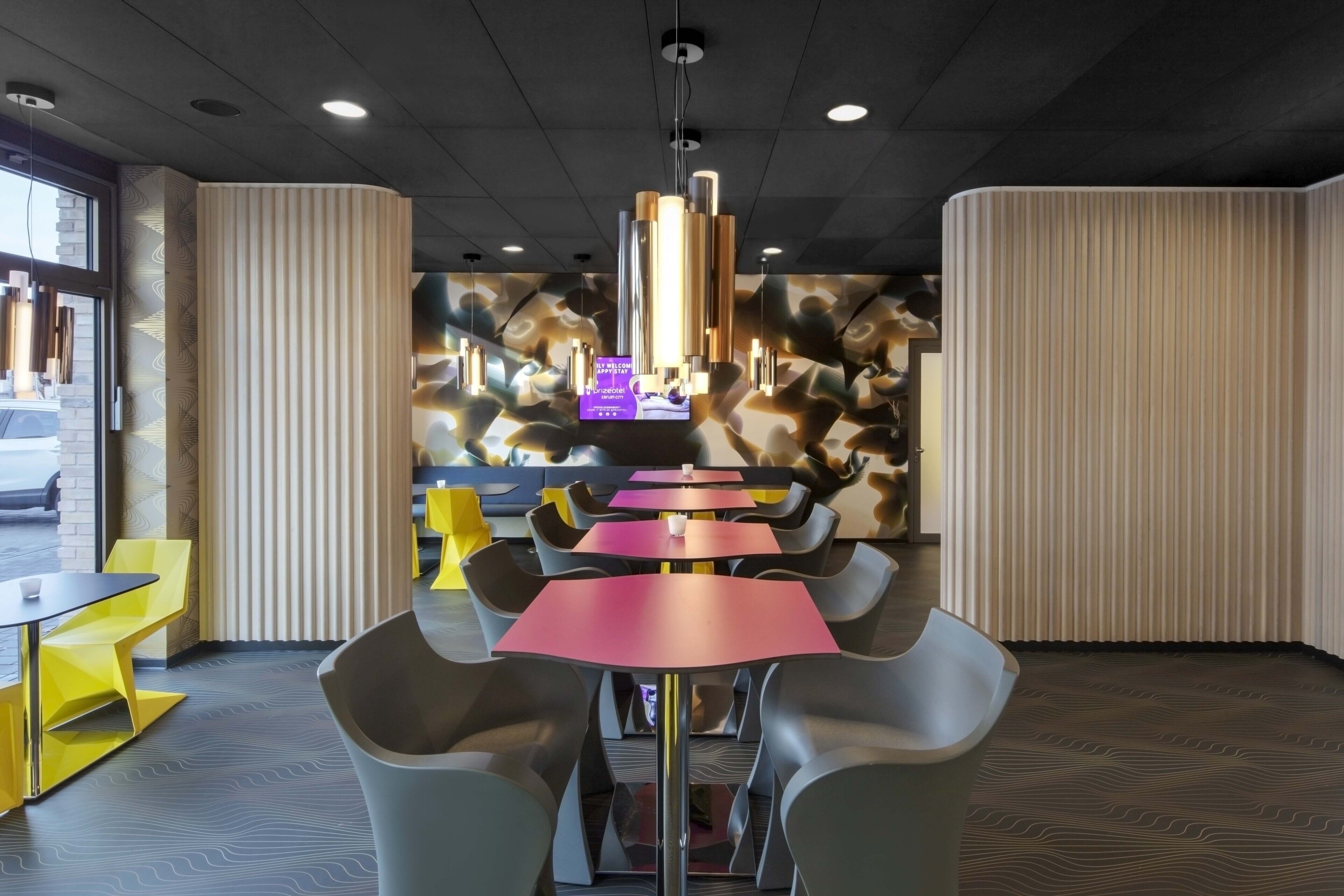 Un intérieur moderne avec un espace salon central, un mur orné de motifs et un écran numérique.