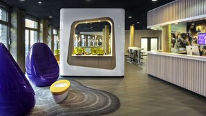 Un área de recepción moderna con un mostrador central, zona de estar y ventanas amplias.