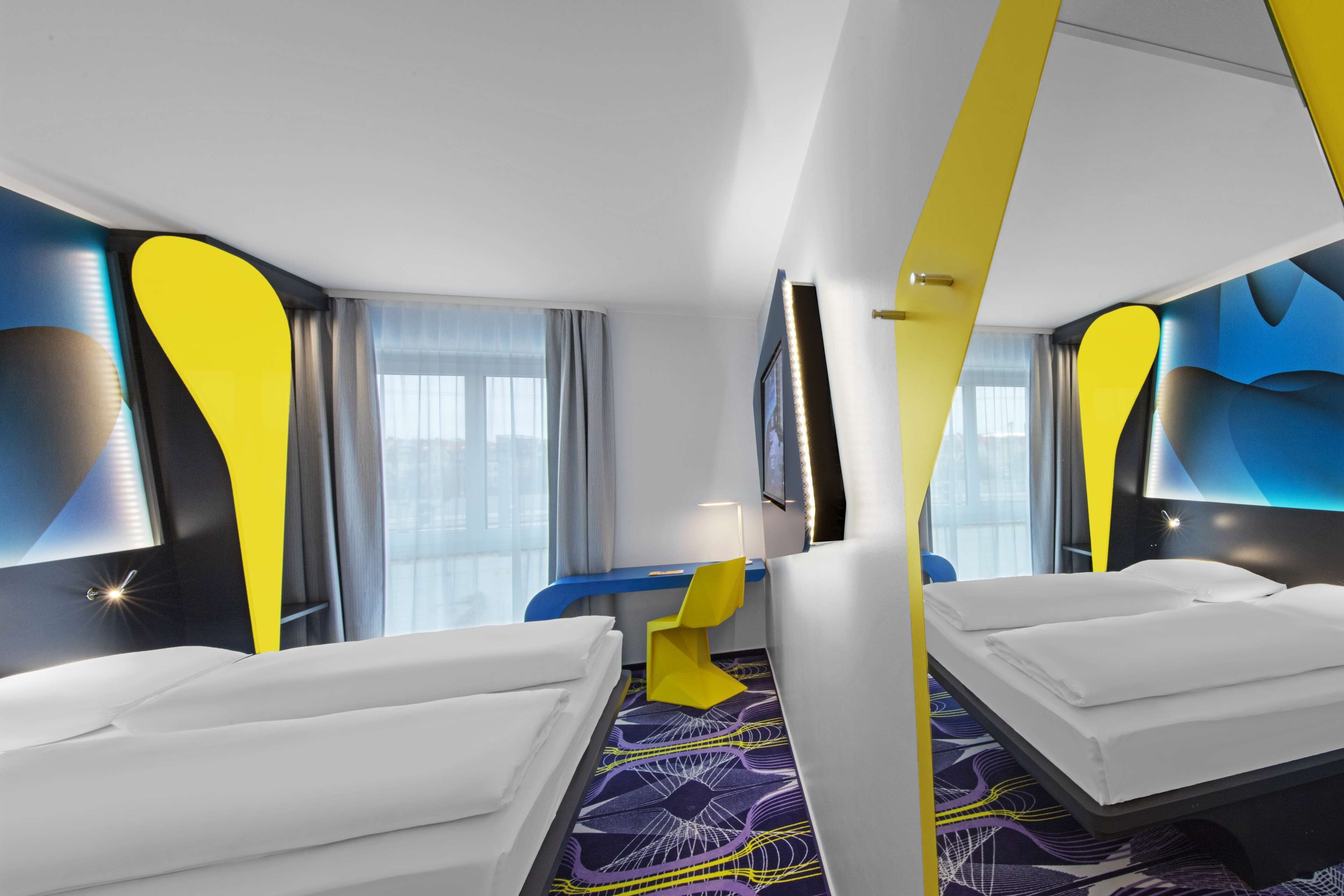 Una habitación de hotel moderna con dos camas, un escritorio y un ventanal grande.