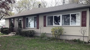 Ein eingeschossiges Haus mit Satteldach, einer Veranda und einem kleinen Vorgarten.