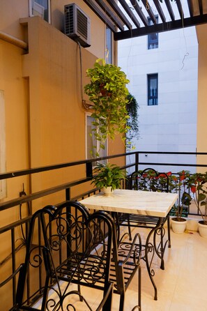 A balcony with a table and chairs, potted plants, and a view of a building.