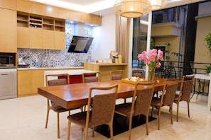 A modern kitchen with wooden cabinets, a built-in microwave, and a dining area with a wooden table and chairs.