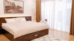 A bedroom with a large bed, a framed picture on the wall, and sheer curtains. - Hanoi Sunflower Westlake Homestay (Hanoi)