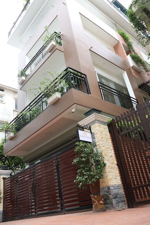 A multi-story residential building with balconies, a gated entrance, and a sign indicating the name 'Sunflower'.