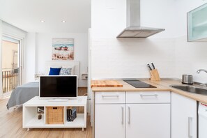 Una cocina moderna con armarios blancos, encimera de madera, estufa integrada y un amplio ventanal.