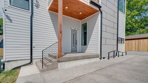 Ein modernes Haus mit einer Holzveranda, einer Haustür und einer kleinen Treppe zum Eingang.