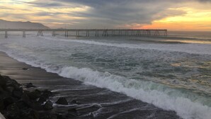 Une jetée qui s’avance dans l’océan, avec des vagues qui se brisent sur le rivage.