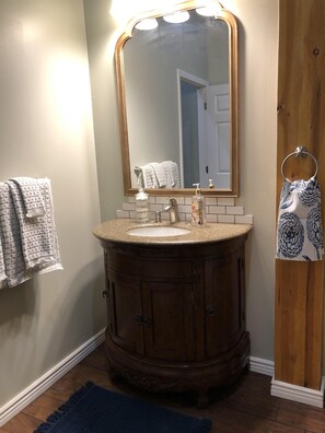 A bathroom with a wooden vanity, a sink, a mirror, and a towel rack. - Court Haus on Main Street (Buffalo)