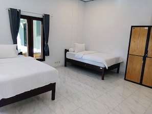 Quarto de hotel com duas camas, um guarda-roupa e uma janela com cortinas.