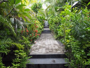 A pathway flanked by lush greenery and a stone staircase leading to a building. - Scuba Tribe Bali dive-resort (Tulamben)