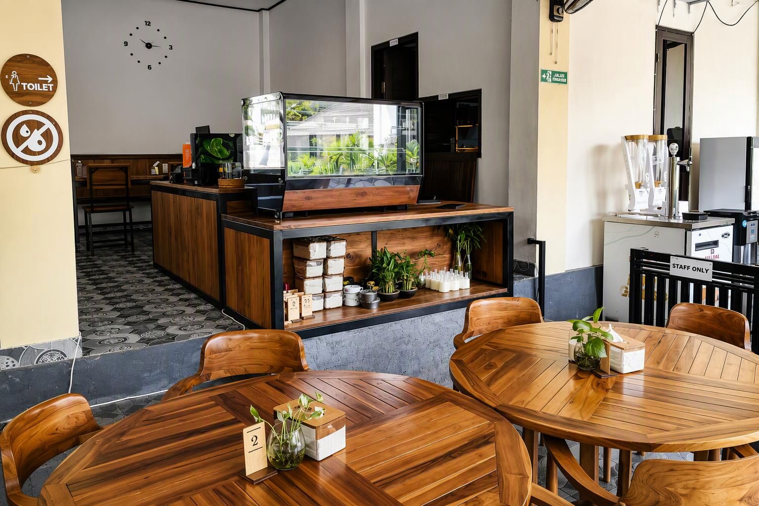 A restaurant with wooden furniture, a TV screen displaying greenery, and a sign indicating a staff-only area.