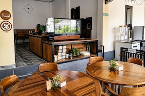 A restaurant with wooden furniture, a TV screen displaying greenery, and a sign indicating a staff-only area. - Scuba Tribe Bali dive-resort (Tulamben)