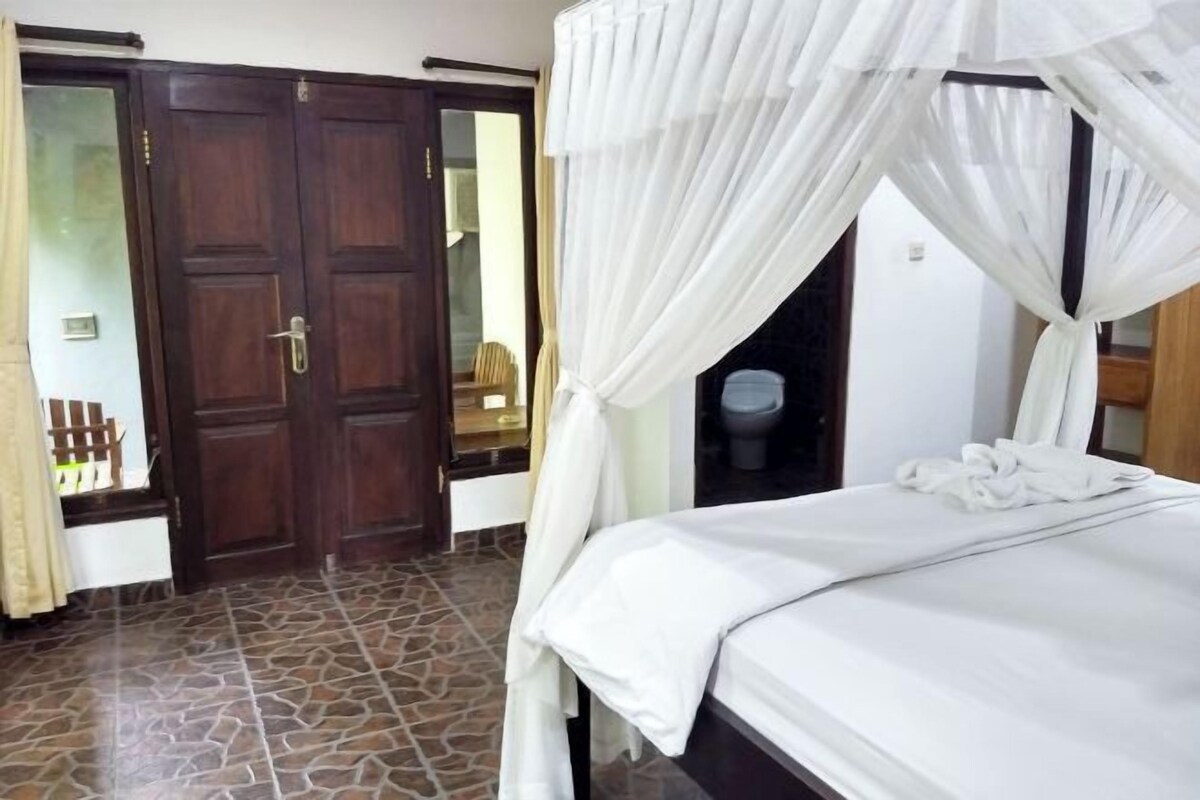 A hotel room with a bed, a wardrobe, and a bathroom.
