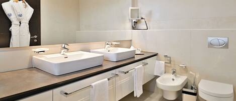 Un baño moderno con dos lavamanos, un bidé y un inodoro.