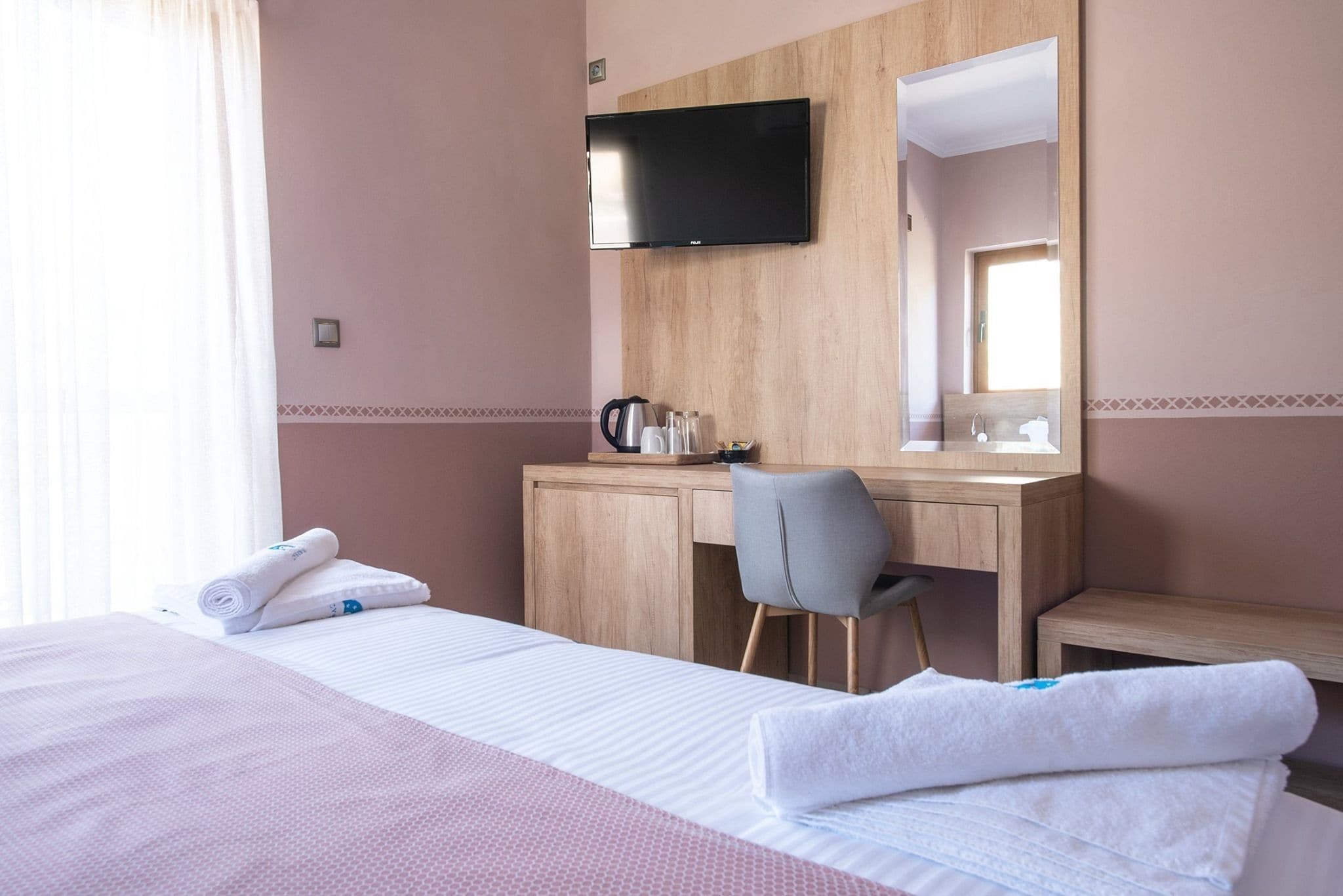 Habitación de hotel con cama, escritorio, silla, televisor y ventana.